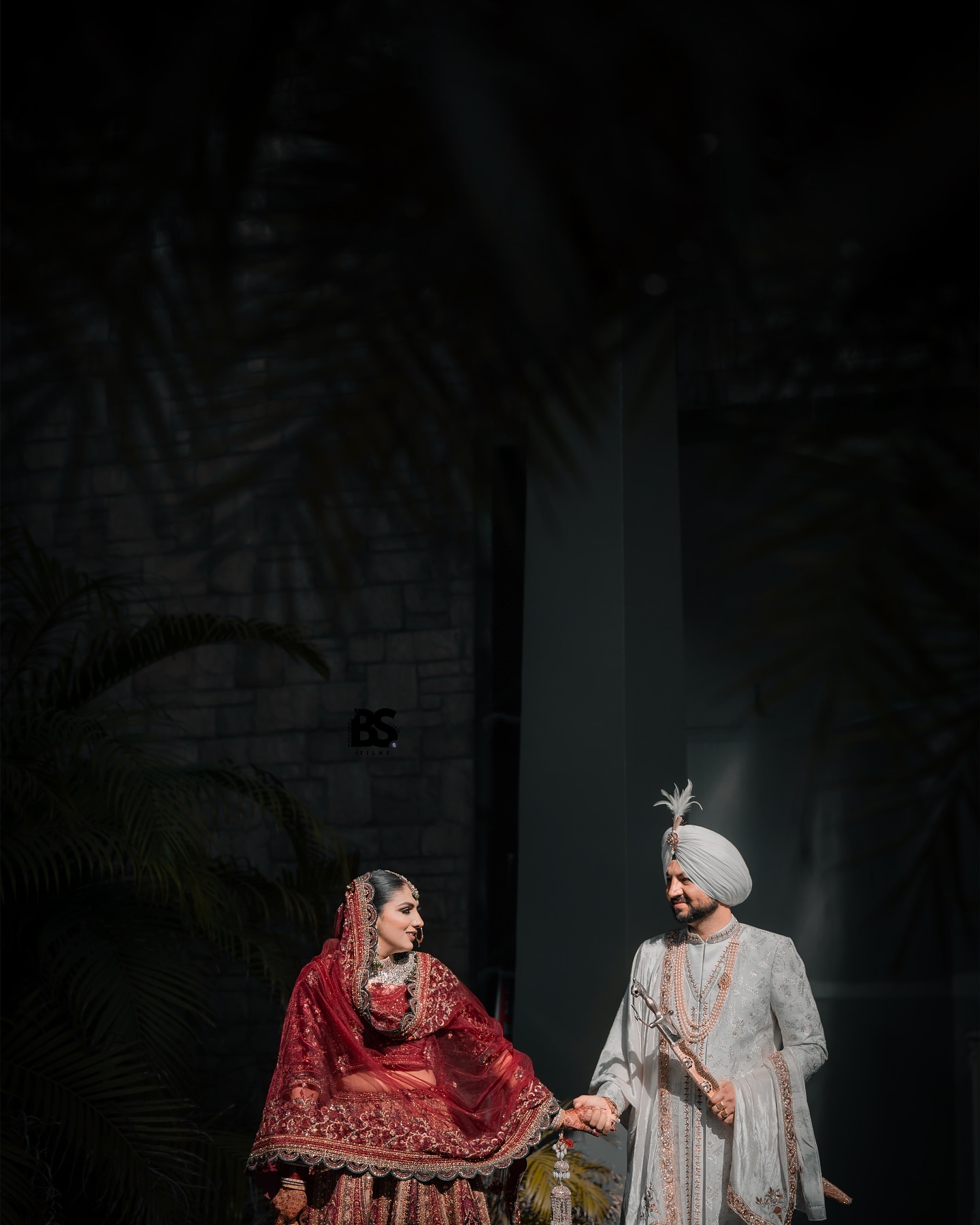 Bride and groom holding hands in dramatic light